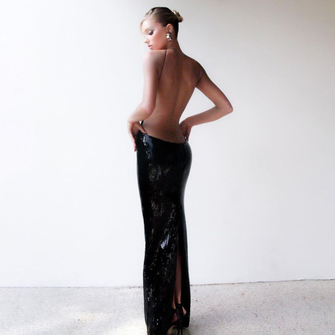 Vestido largo de lentejuelas con escote halter y espalda descubierta con corte de discoteca