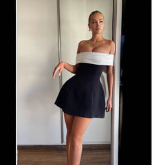 Vestido con hombros descubiertos, color blanco y negro en contraste, cintura ajustada, diseño swing y lazo