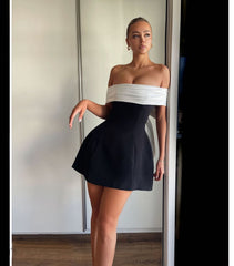 Vestido con hombros descubiertos, color blanco y negro en contraste, cintura ajustada, diseño swing y lazo
